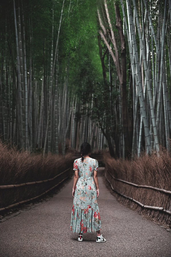 Woman in a dress standing in front of a forest full of bamboo